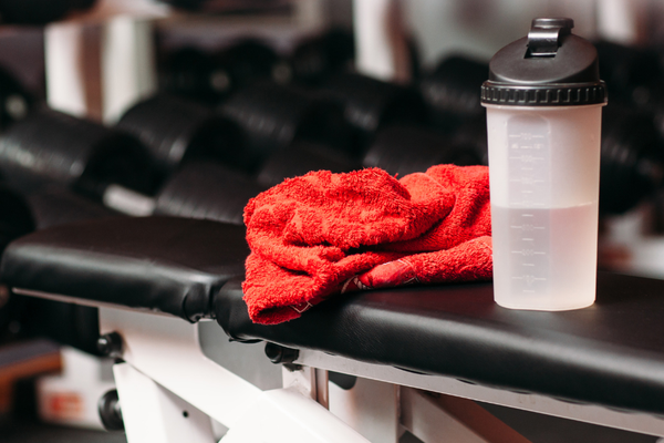 serviette et bouteille posées sur un banc de musculation dans une salle de sport