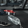téléphone et gourde posés au sol dans une salle de sport